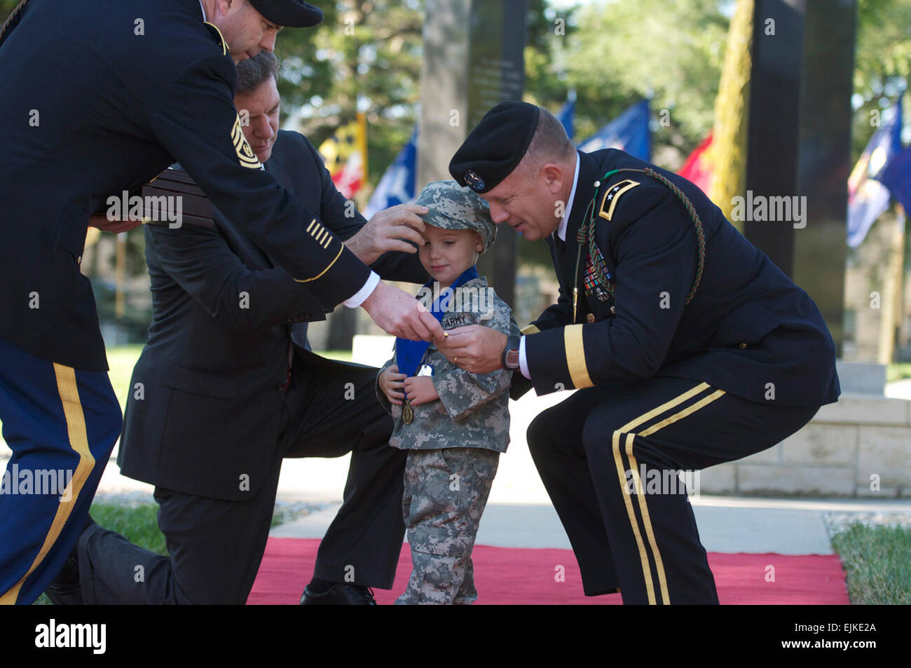 Da sinistra il comando Sgt. Il Mag. Jim Thomson, Kansas Gov. Sam Brownback, e 1a Divisione di Fanteria Comandante Generale Il Mag. Gen. William Mayville presente un medaglione a Michael Cook Jr. III durante un 9/11 cerimonia di commemorazione a Fort Riley, Kan., domenica. Cuocere il padre morì servendo con la divisione di seconda brigata pesante Team di combattimento in Iraq questo giugno. Sgt. Roland Hale, 1INF. Div. Affari pubblici Foto Stock