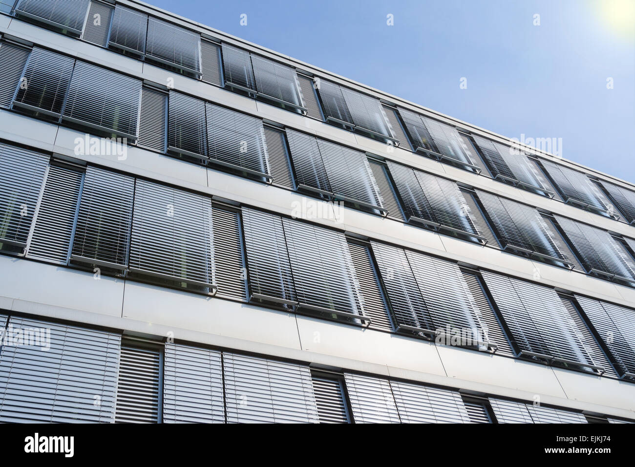 Facciata del moderno ed alto edificio di uffici con coperte windows veneziane contro il cielo blu Foto Stock