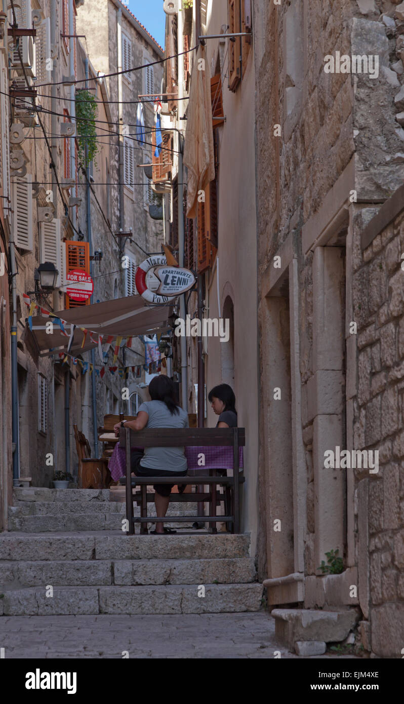 Turisti orientali in un caffè di vecchia città di Korcula strada stretta e vecchi edifici in pietra con piccoli ristoranti. Foto Stock