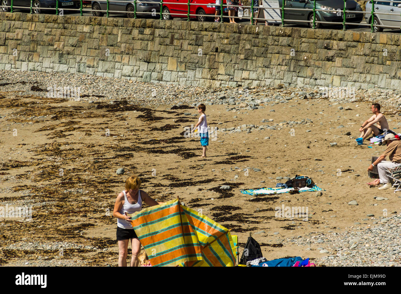 La gente a prendere il sole sulla spiaggia a est a Criccieth, il Galles del Nord. Foto Stock