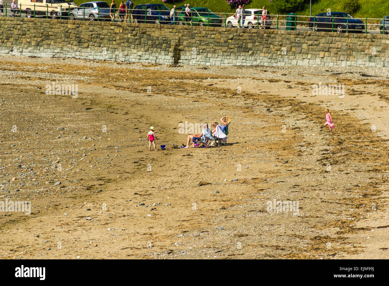 La gente a prendere il sole sulla spiaggia a est a Criccieth, il Galles del Nord. Foto Stock