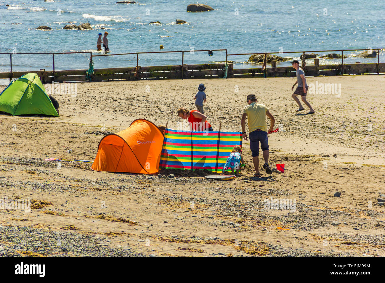 La gente a prendere il sole sulla spiaggia a est a Criccieth, il Galles del Nord. Foto Stock