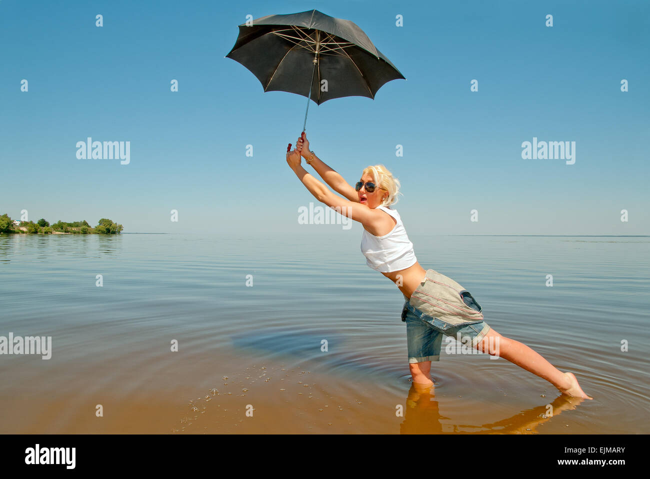 Ragazza giovane con un ombrello passeggiate in acqua Foto Stock