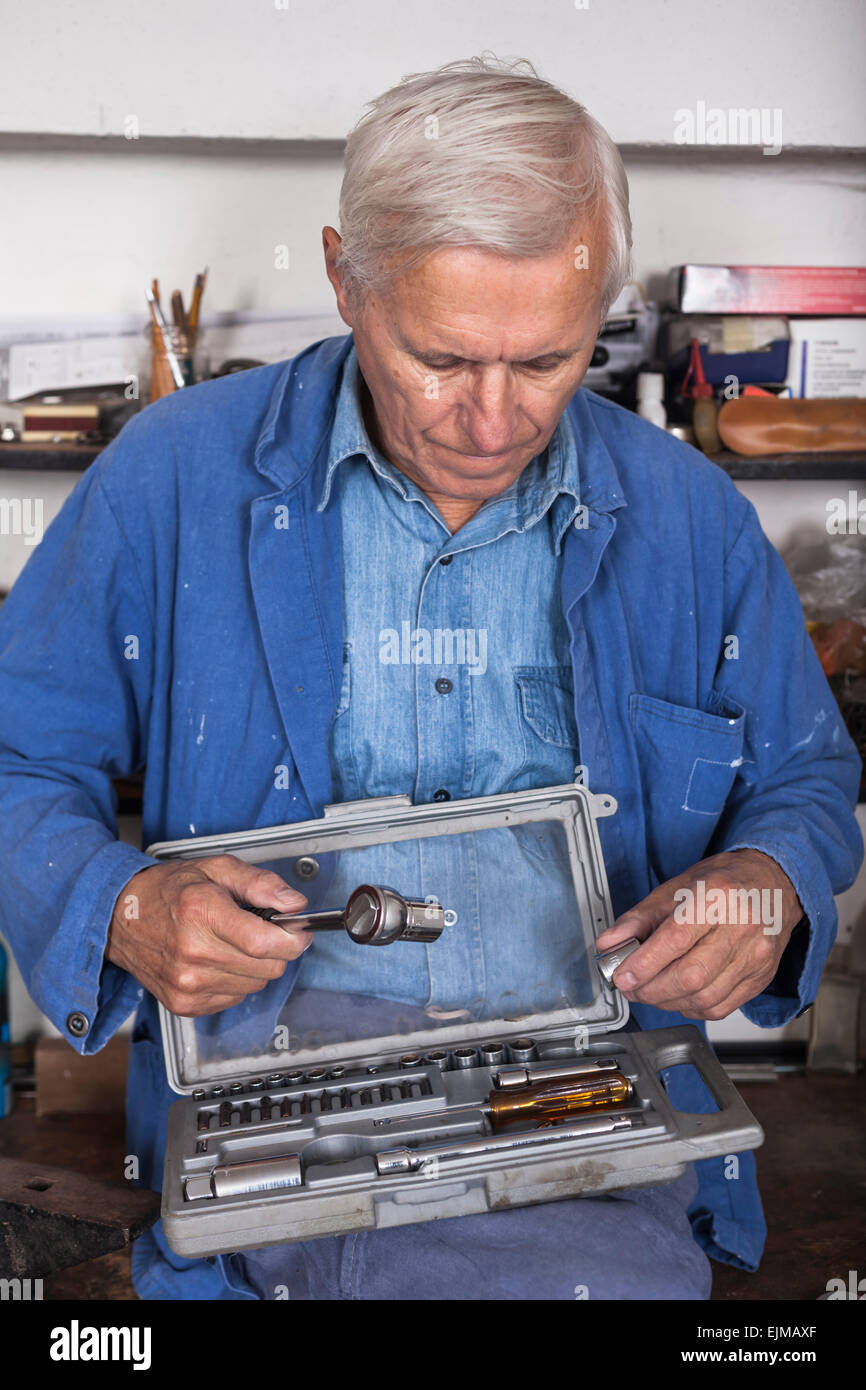 Lavoratori anziani con cricchetto e strumenti in officina. Foto Stock
