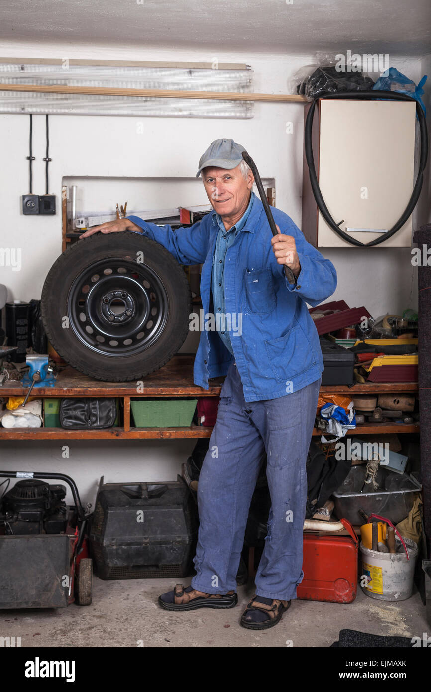 Ritratto di lavoratori anziani con un pneumatico e l'attrezzo in piedi nel garage. Foto Stock