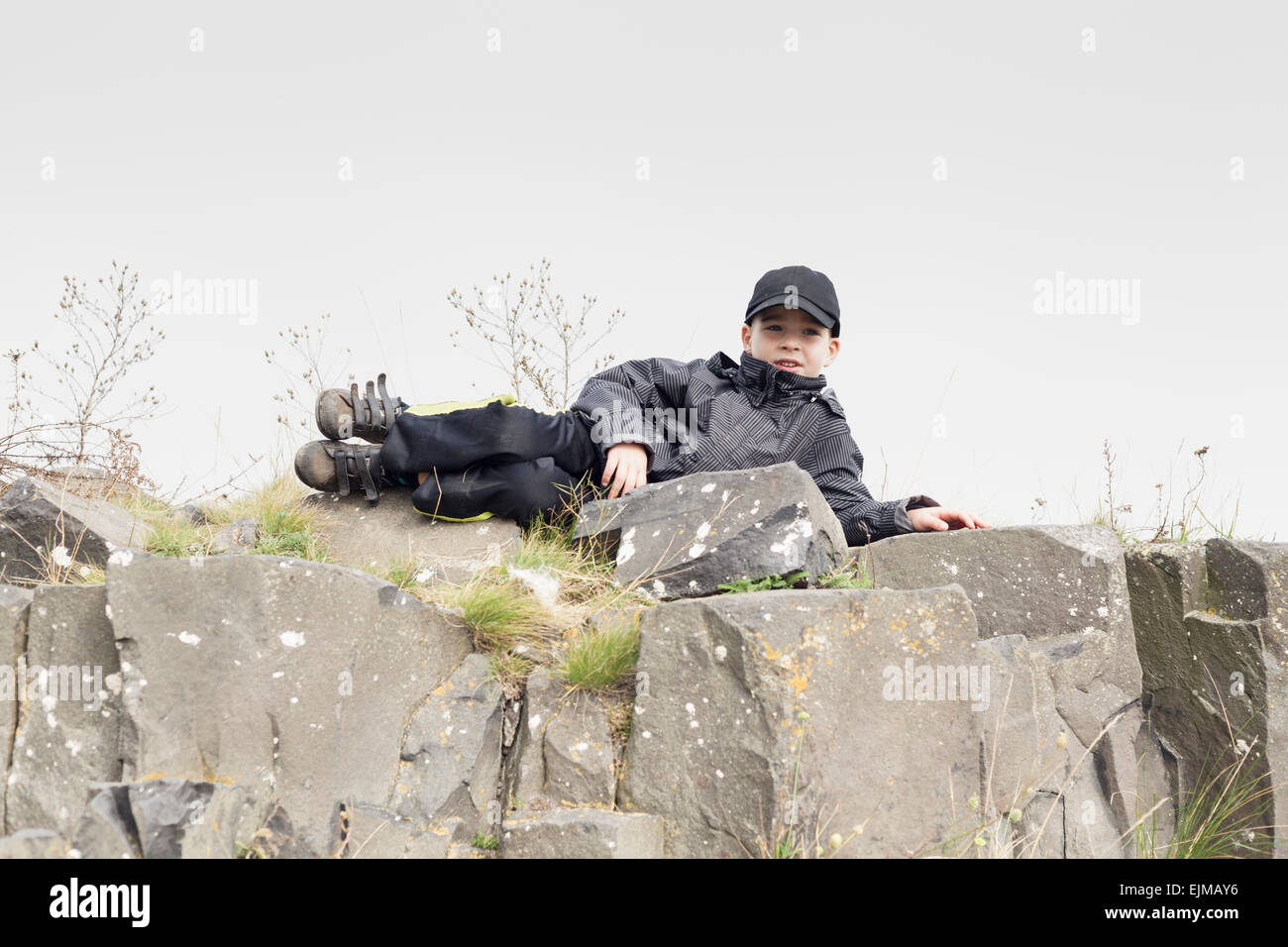 Ritratto di un bambino ragazzo rilassante sulla roccia. Foto Stock
