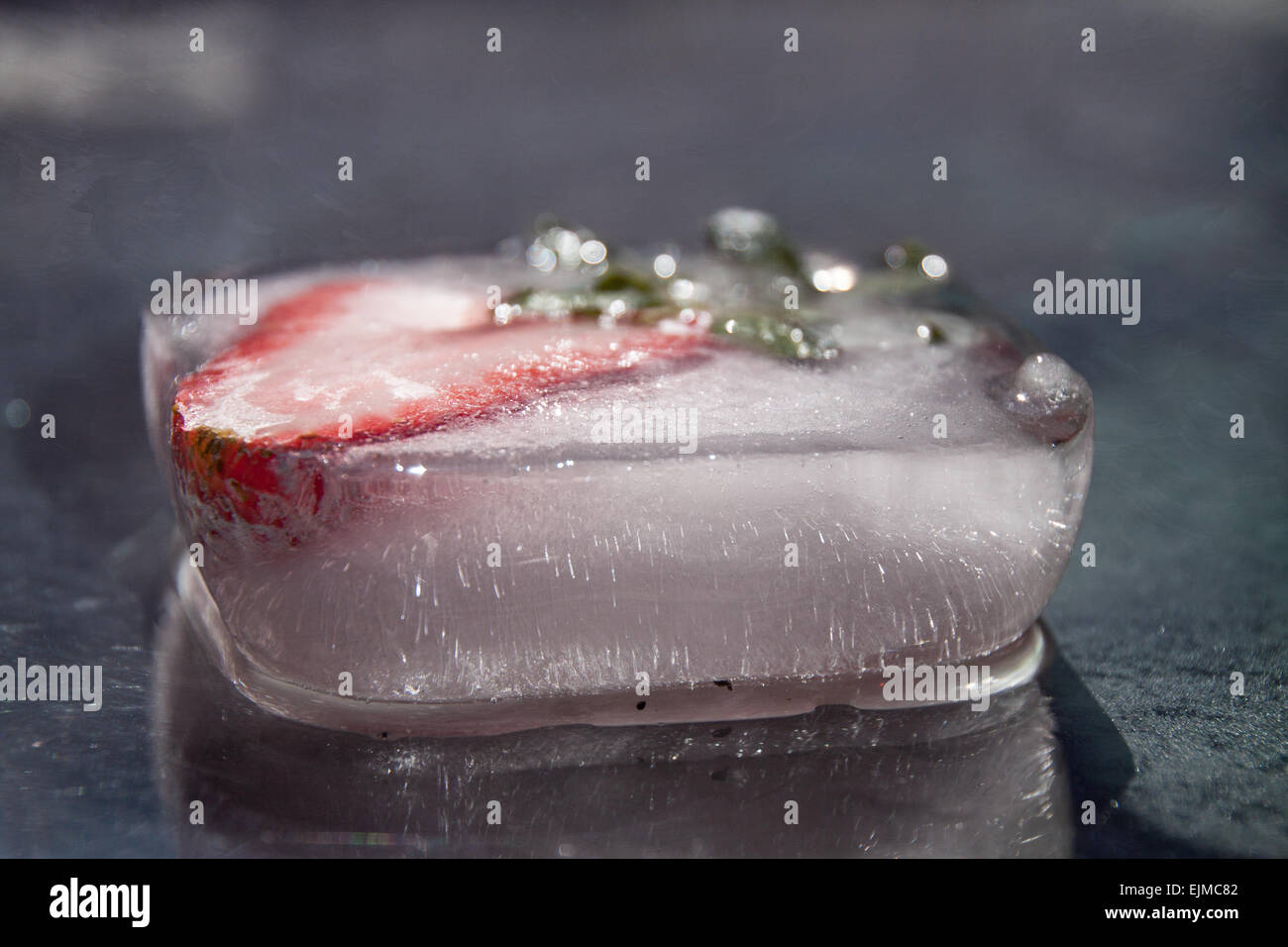 Fotografia di cibo, creatività con ghiaccio e fragole. Fragole congelate all'interno di un cubo di ghiaccio. Foto Stock