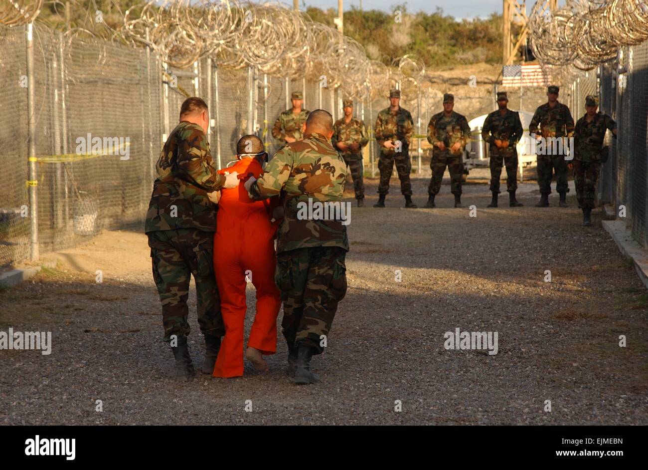US Army polizia militare escort un detenuto in una tuta arancione e vincoli a una cella a Camp X-Ray Delta Gennaio 11, 2002 a Guantánamo, a Cuba. I detenuti sono stati catturati nelle guerre in Iraq e in Afghanistan. Foto Stock