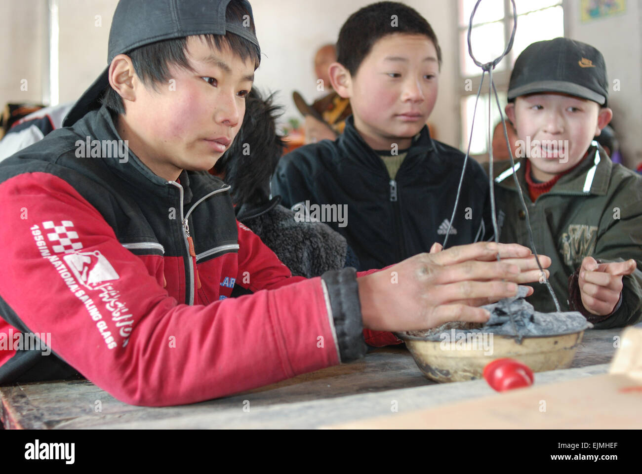 Gli studenti stringersi intorno a un carbone caldo per riscaldare le loro mani in Lantian, Xi'an, Cina. Foto Stock