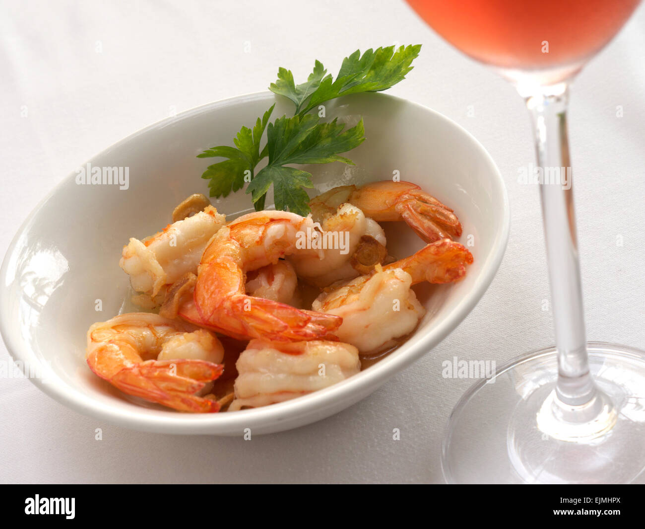 Gamberi King in aglio con un bicchiere di champagne rosato sul tavolo del ristorante all'aperto Foto Stock