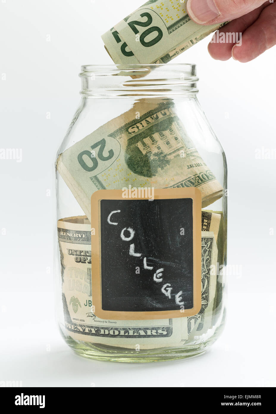 Mano caucasica mettere soldi in un barattolo di vetro su sfondo bianco con gesso nero etichetta o pannello e utilizzato per il salvataggio di US dollar bi Foto Stock