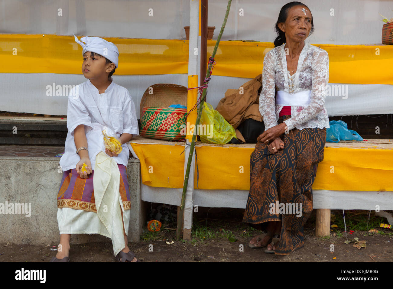 Una donna e un bambino che riposano dopo una cerimonia tradizionale vicino al tempio acquatico Ulun Danu Bratan a Bedugul, Tabanan, Bali, Indonesia. Foto Stock