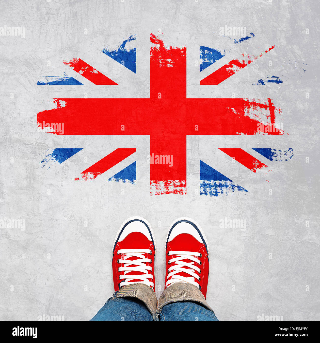 British Urban Concept della Gioventù, piedi in rosso Sneakers dal di sopra in piedi nella parte anteriore del grunge Gran Bretagna bandiera. Foto Stock