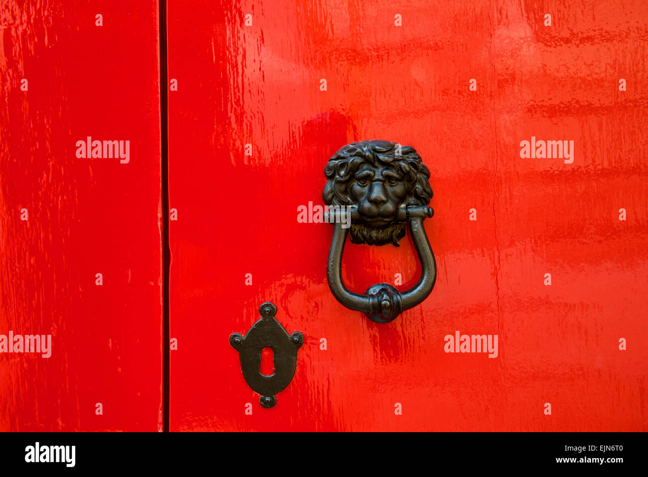 Vecchia porta rossa con testa leone battenti di metallo, Mdina, Malta. Foto Stock