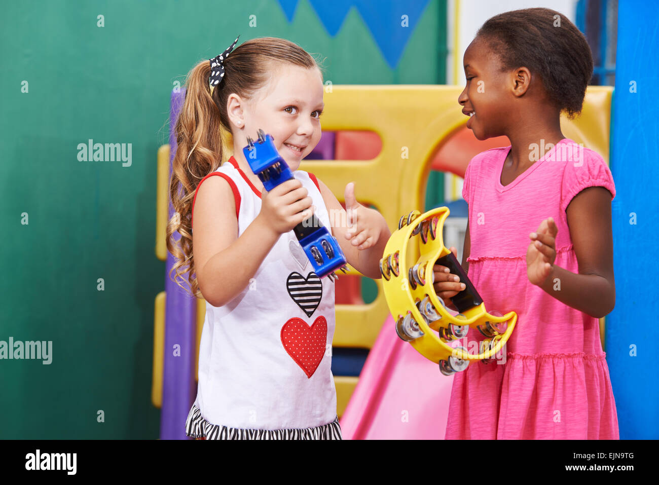 Due ragazze di riproduzione di musica con il tamburello in un kindergarten Foto Stock