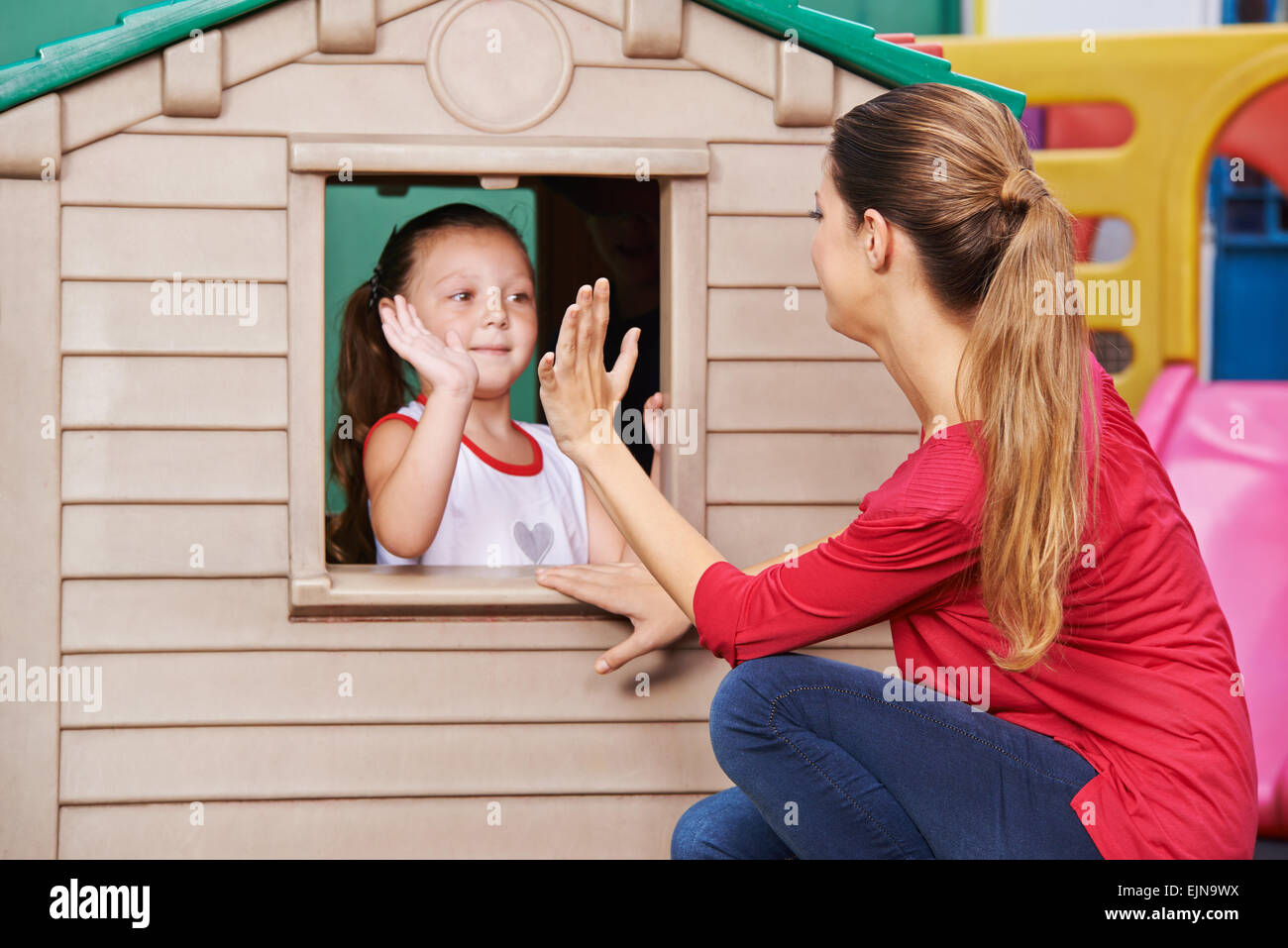 Insegnante di vivaio e la ragazza che gioca battimani gioco insieme nella scuola materna Foto Stock