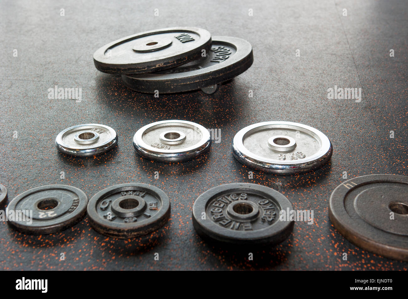 Set di pesi di zavorra a piastre disposte sul pavimento nero Foto Stock