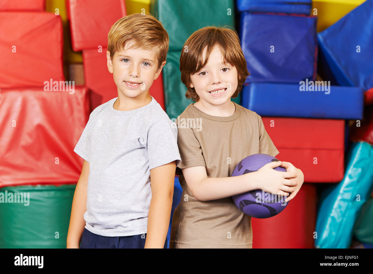 Due ragazzi in piedi con una palla nella palestra di una scuola materna Foto Stock