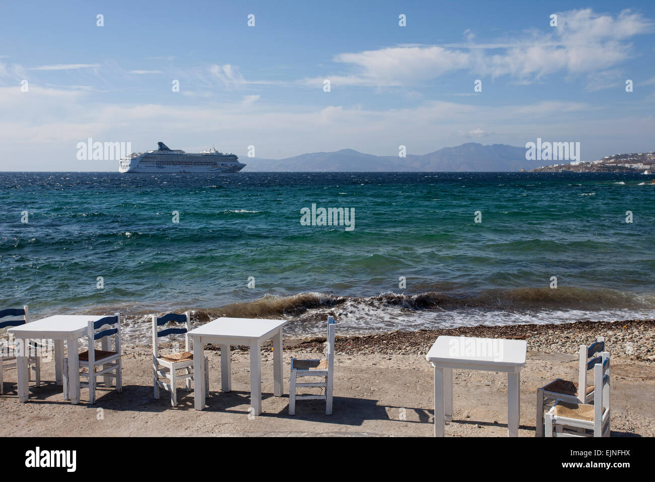 Mykonos, Grecia cafe racconti sul Mare Mediterraneo a riva con la nave di crociera in background Foto Stock