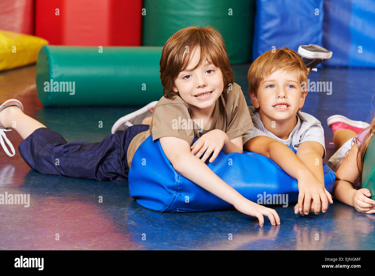 Due ragazzi in palestra posa su un cuscino nella scuola elementare Foto Stock