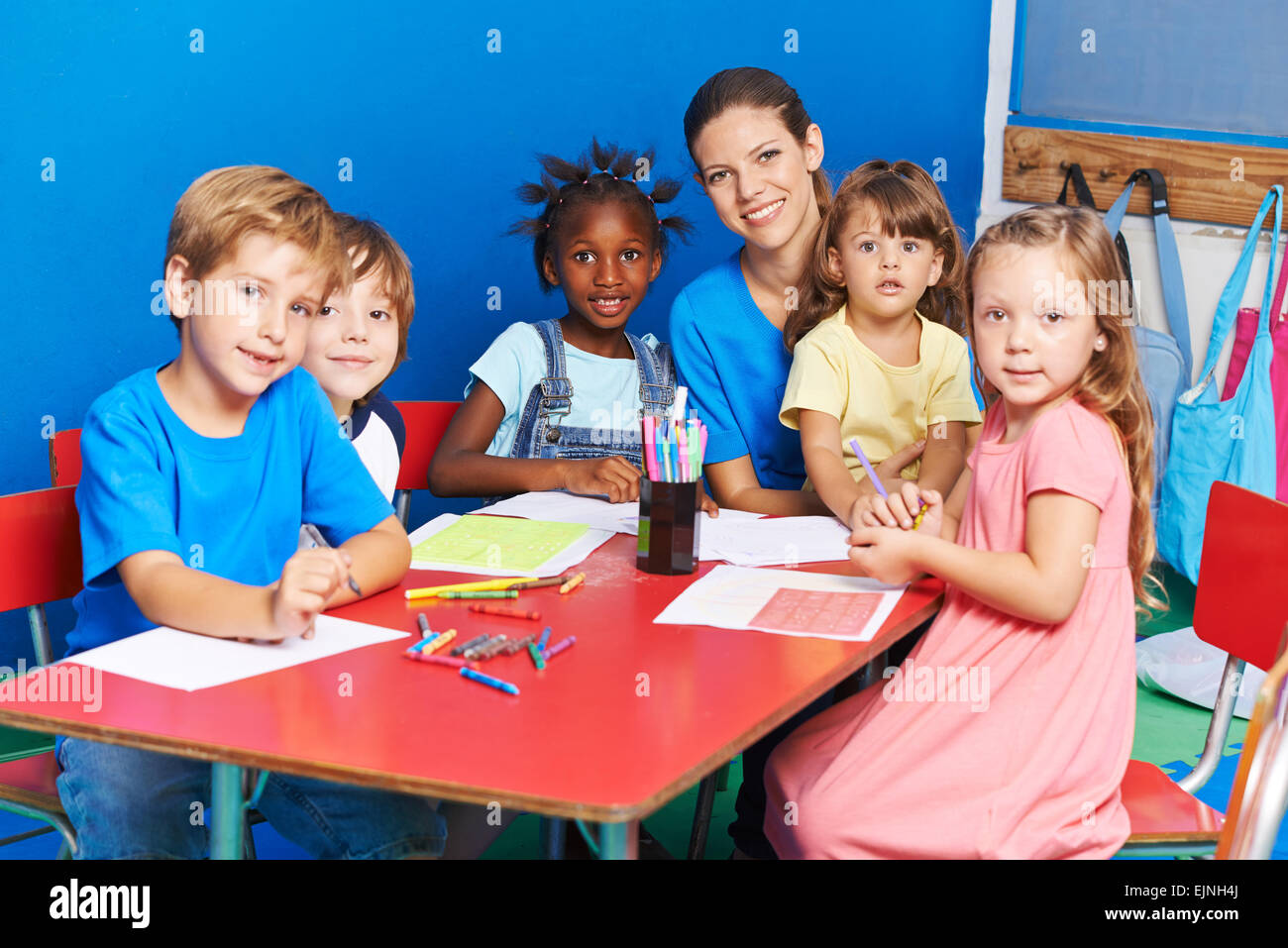 Gruppo di bambini la pittura su tavola con nursery insegnante in una scuola  materna Foto stock - Alamy