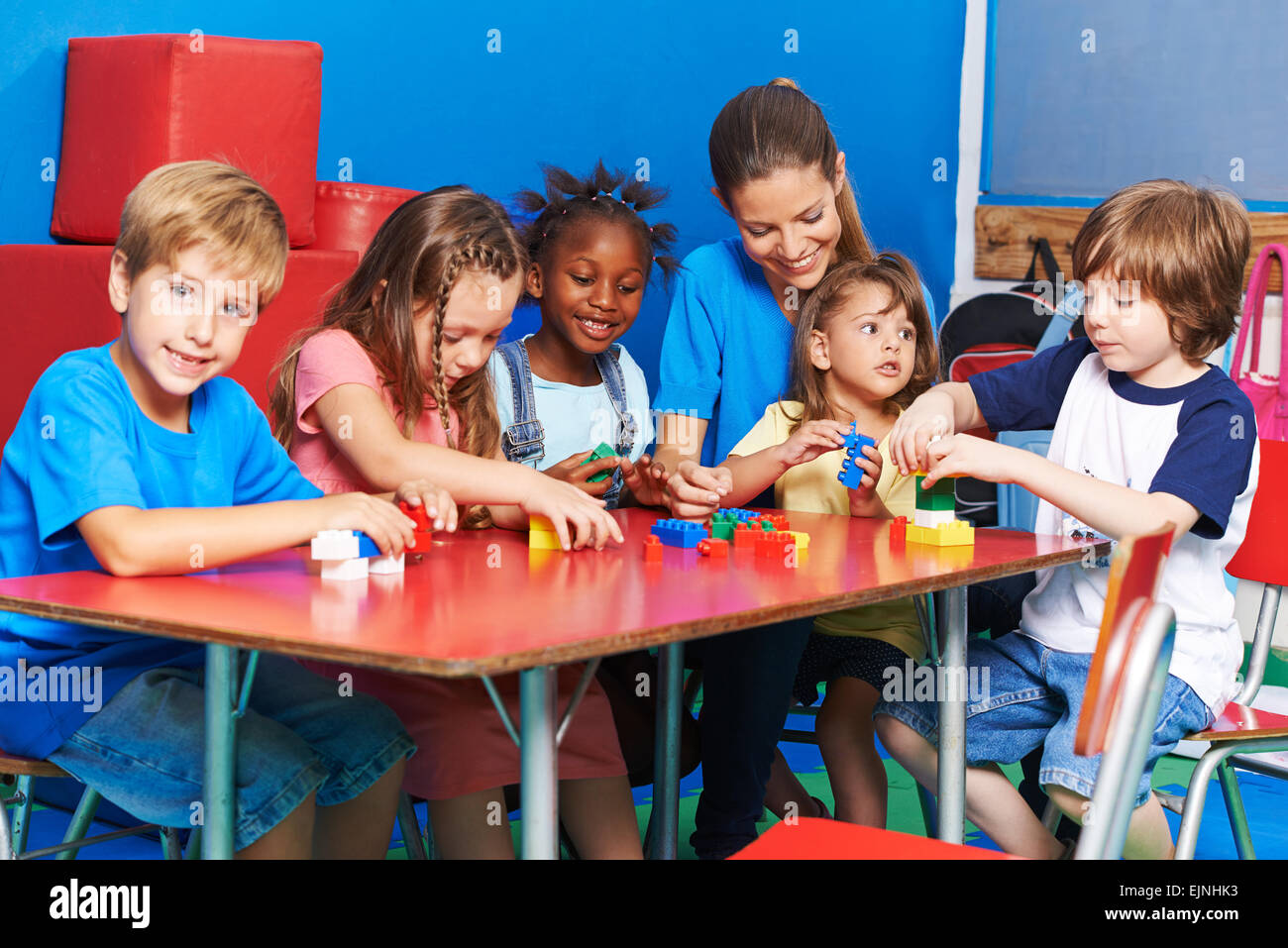 Bambini Un insegnante giocando con la costruzione di blocchi insieme in età prescolare Foto Stock