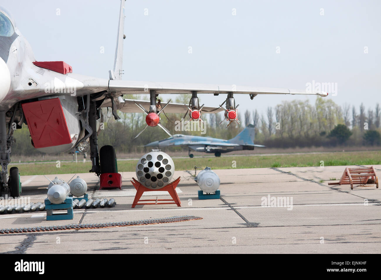 Jet da combattimento sul campo d'aviazione con la sua esposizione di munizioni. Un altro piano è sulla pista Foto Stock