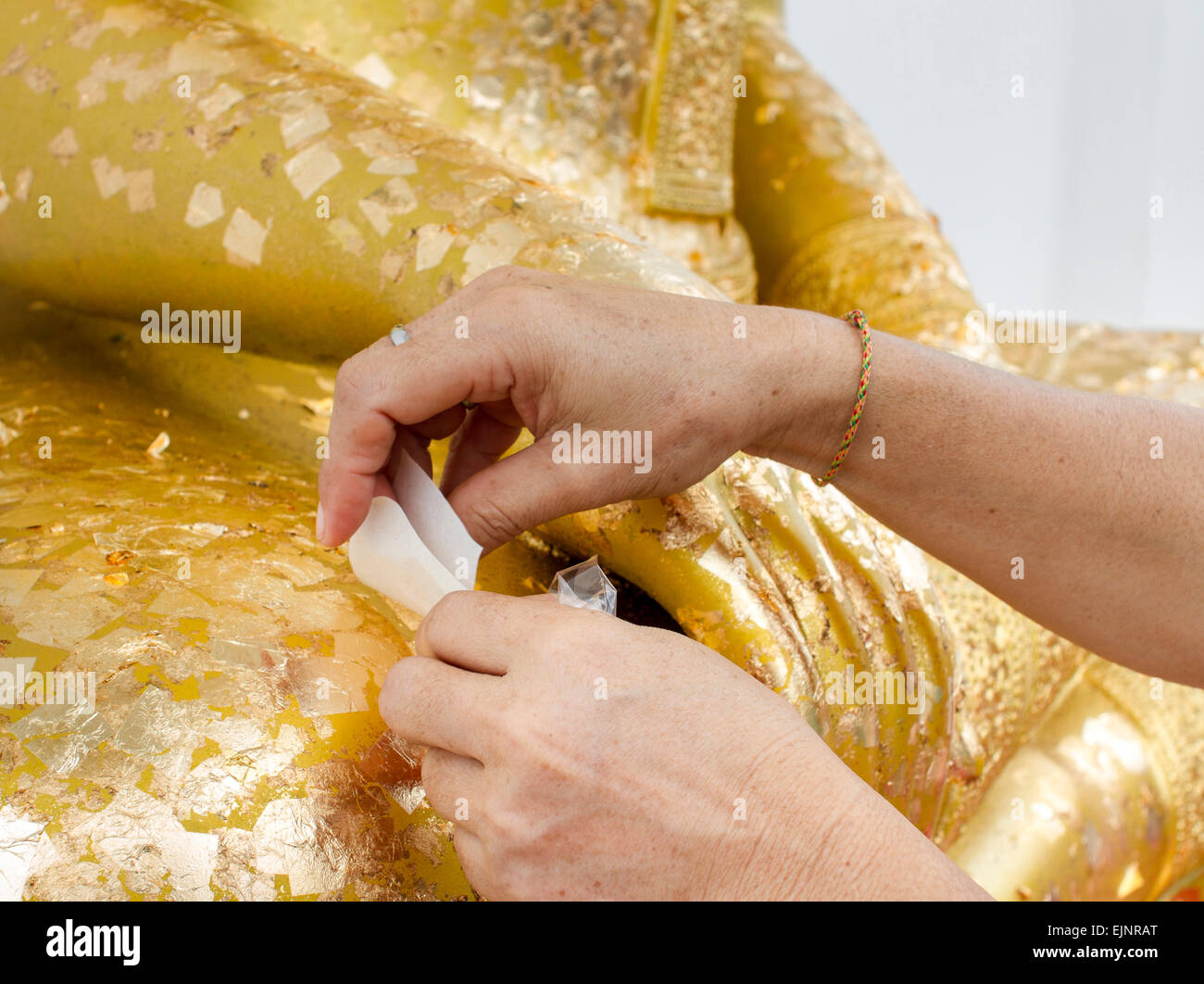 Donna paste adesive foglia oro su golden statua del Buddha Foto Stock
