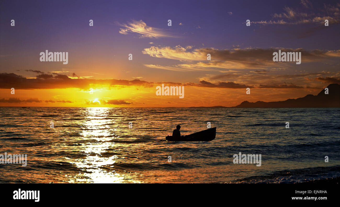 Silhouette di una piccola barca da pesca sul tramonto. Foto Stock