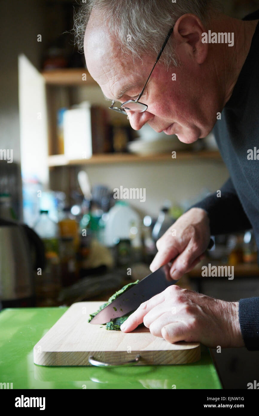 Un uomo tritare erbe o foglie per la cottura. Foto Stock