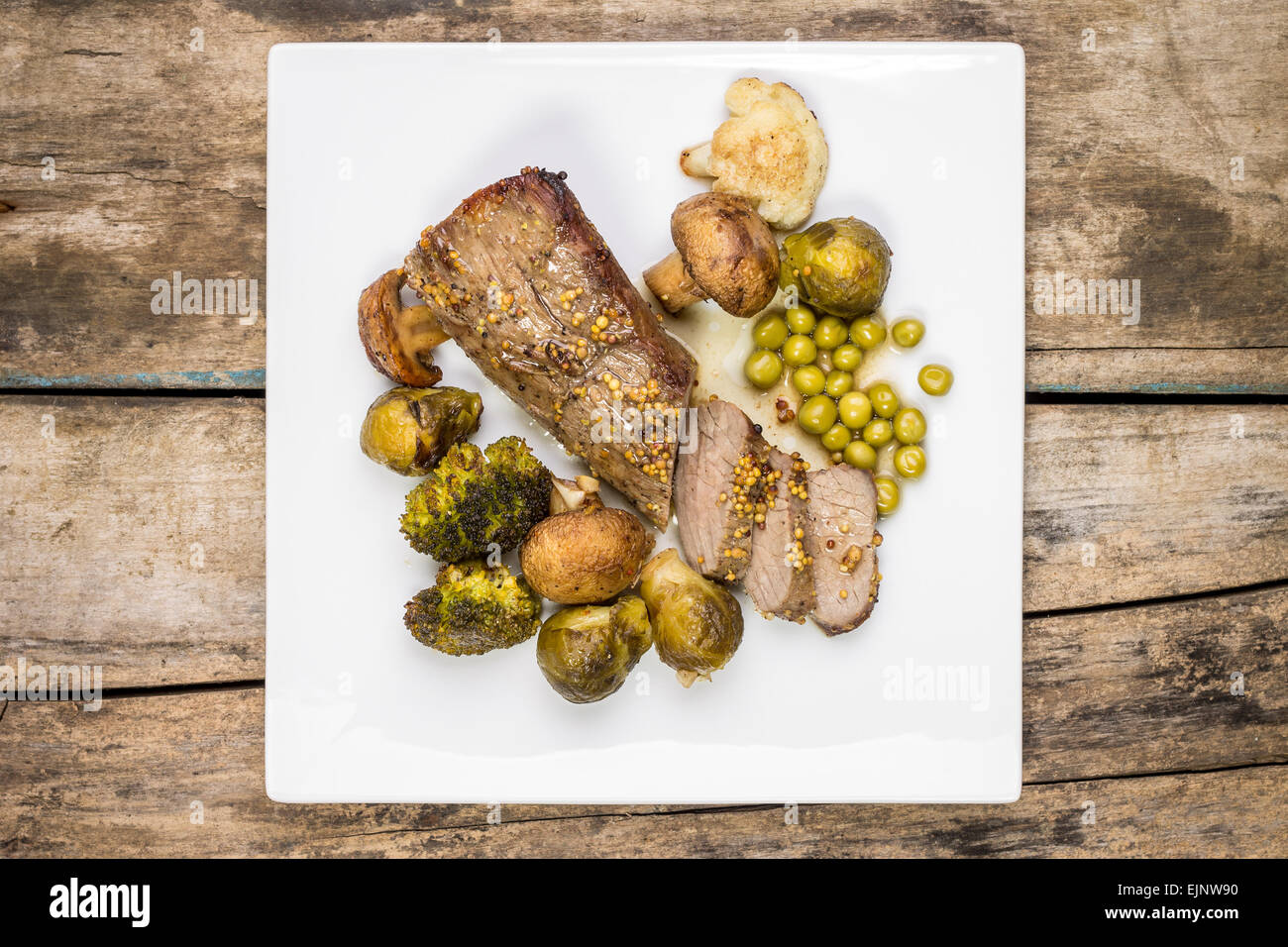 Arrosto di carne di manzo tagliata in fetta con broccoli, cavolini di Bruxelles e funghi sulla piastra bianca. Top visualizza immagine della cena a base di carne Foto Stock