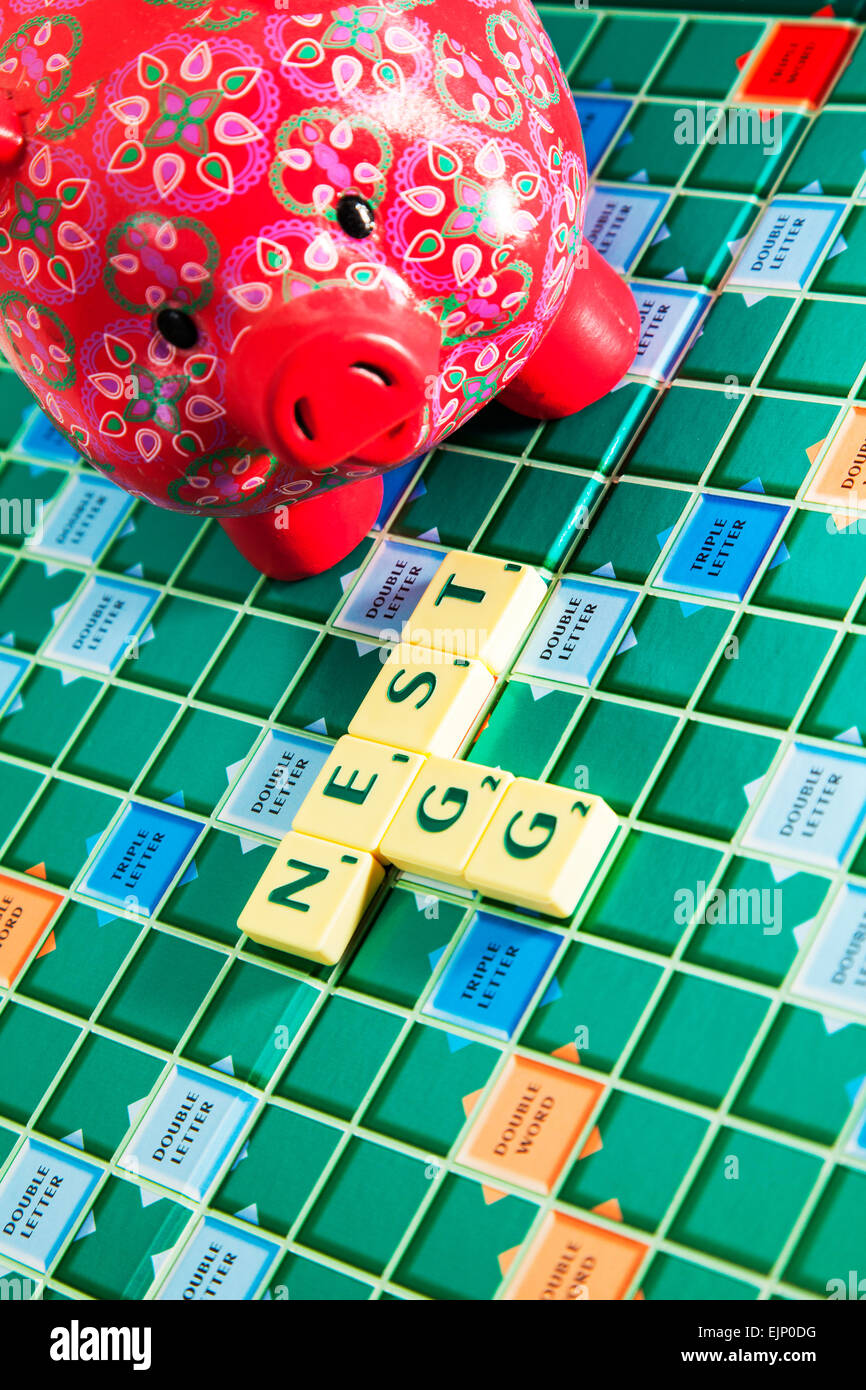 Salvadanaio nest egg risparmi soldi pound monete pension salvare Rainy day parole fondo usando piastrelle scrabble per illustrare l'ortografia Foto Stock