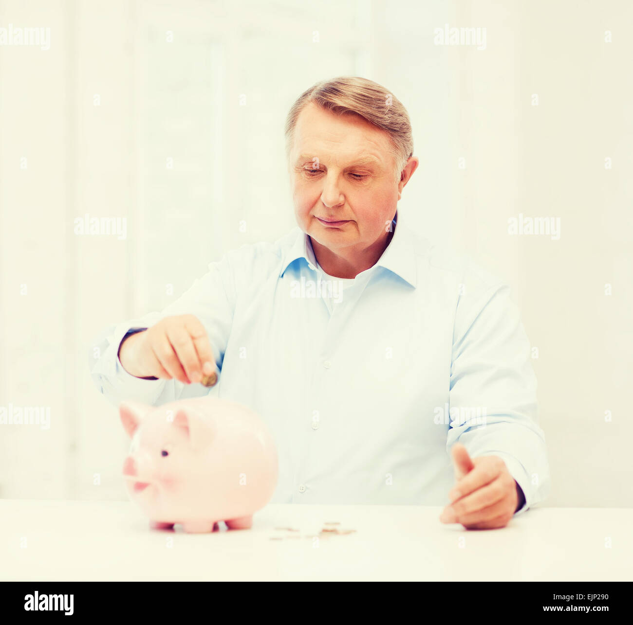 Il vecchio uomo di mettere moneta nella grande salvadanaio Foto Stock