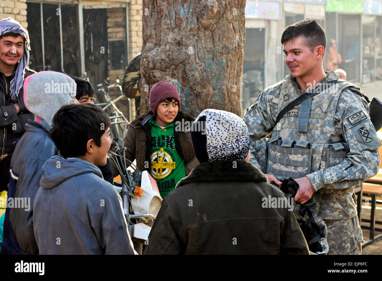 Stati Uniti Esercito 1Lt. Pierce Pettis colloqui per i bambini del villaggio come Stati Uniti e soldati afgani caricare i banchi di scuola sui loro veicoli nei pressi di Bagram Airfield, Afghanistan, Dic 30, 2010. Le truppe degli Stati Uniti sono assegnati alla 87th lottare contro il supporto del battaglione di supporto, 101st supporto brigata. I nuovi banchi sono parte del primo grande progetto tra il battaglione e forze afghane. Pfc. Michael Vanpool Foto Stock