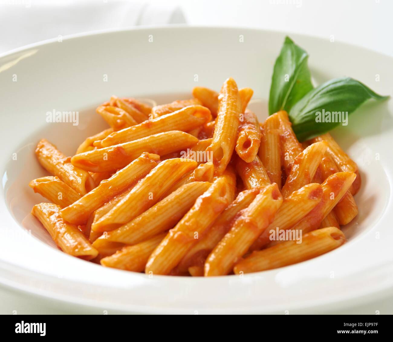 Taliana semplici tubi di penne di pasta mescolata con pomodoro e basilico salsa semplice cena in un ristorante o la cura casa sana Foto Stock