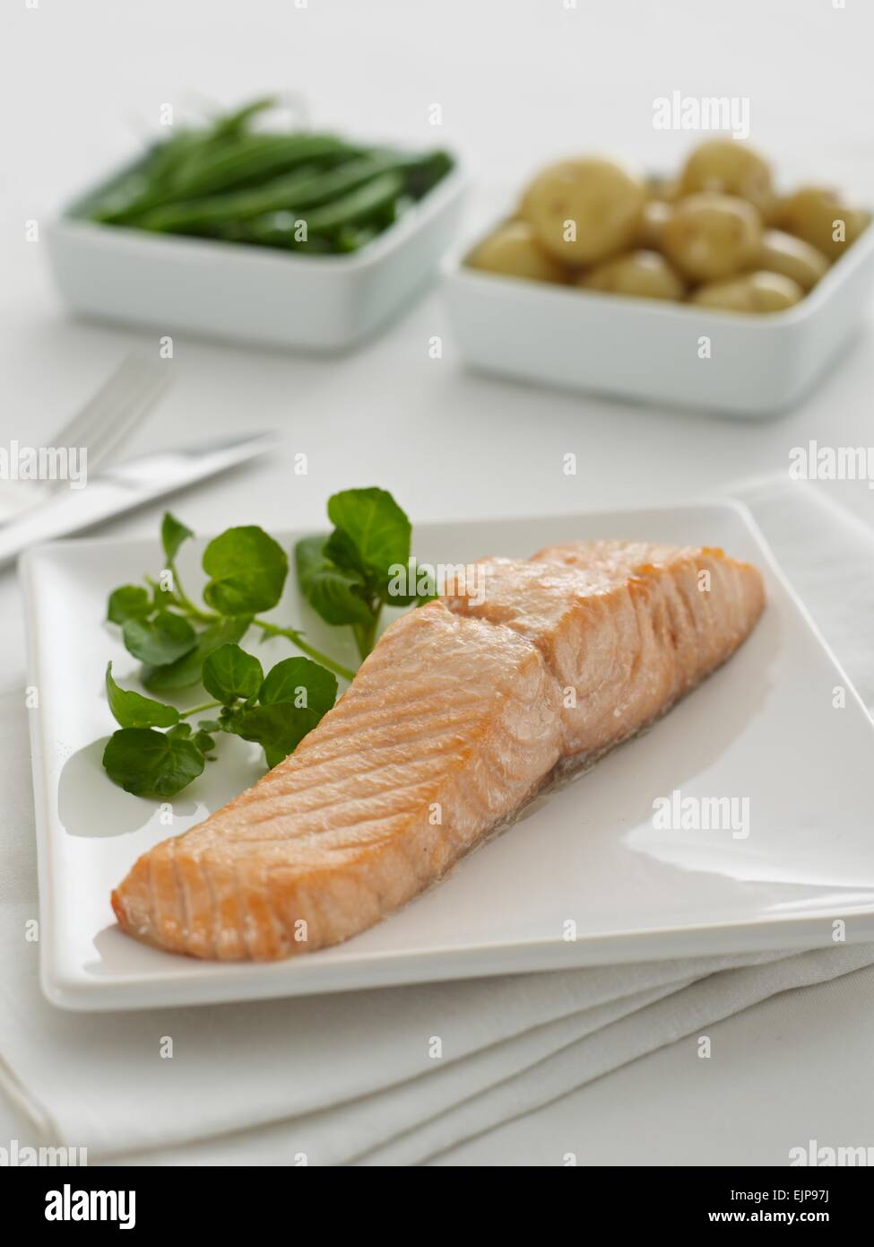 Semplice pasto placcati di pan pianura fritte filetto di pesce Salmone con crescione e distinti piatti quadrati di verdure Foto Stock