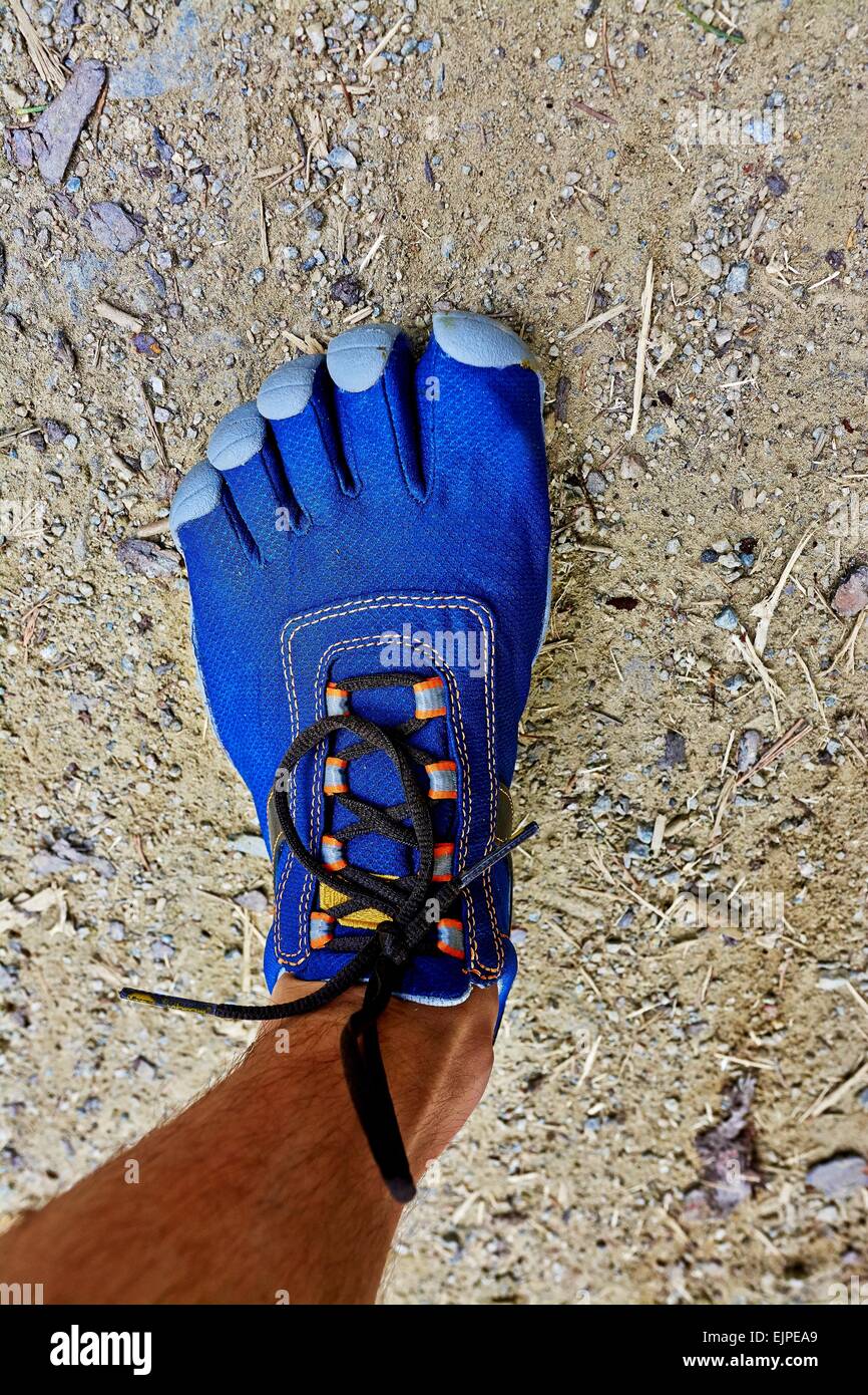 La gamba e il piede di un uomo rivolto con blue sport scarpe con cinque dita sistema. Foto Stock