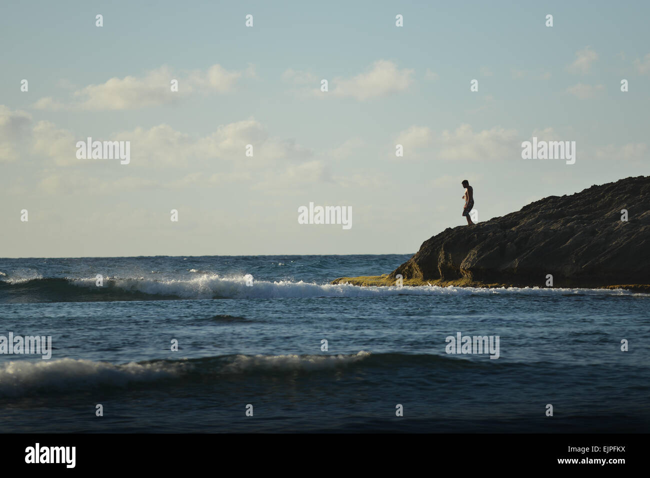 Uomo in piedi sul bordo di una formazione rocciosa a spiaggia Jobos. Isabela, Puerto Rico. Territorio statunitense. Isola dei caraibi. Foto Stock