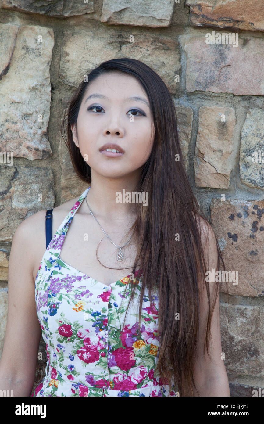 Bella donna asiatica all'aperto in un abito fiorito, guardando pensieroso Foto Stock