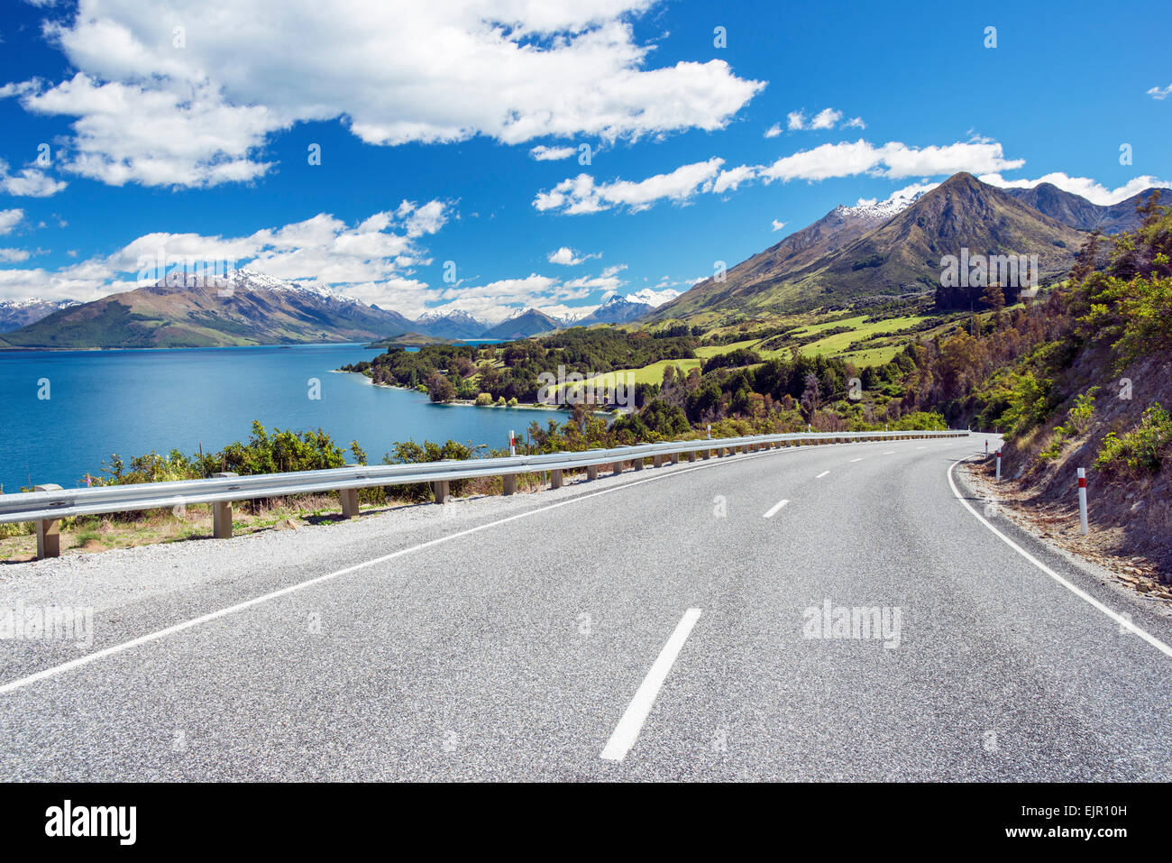 Il Glenorchy Queenstown Road in esecuzione attraverso terreni coltivati e tra il Lago Wakatipu e sulle montagne Foto Stock