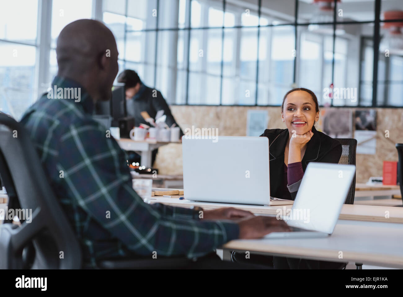 Giovani designer creativi avente cordiale colloquio presso l'ufficio. African American donna seduta al tavolo per discutere il lavoro con coll Foto Stock