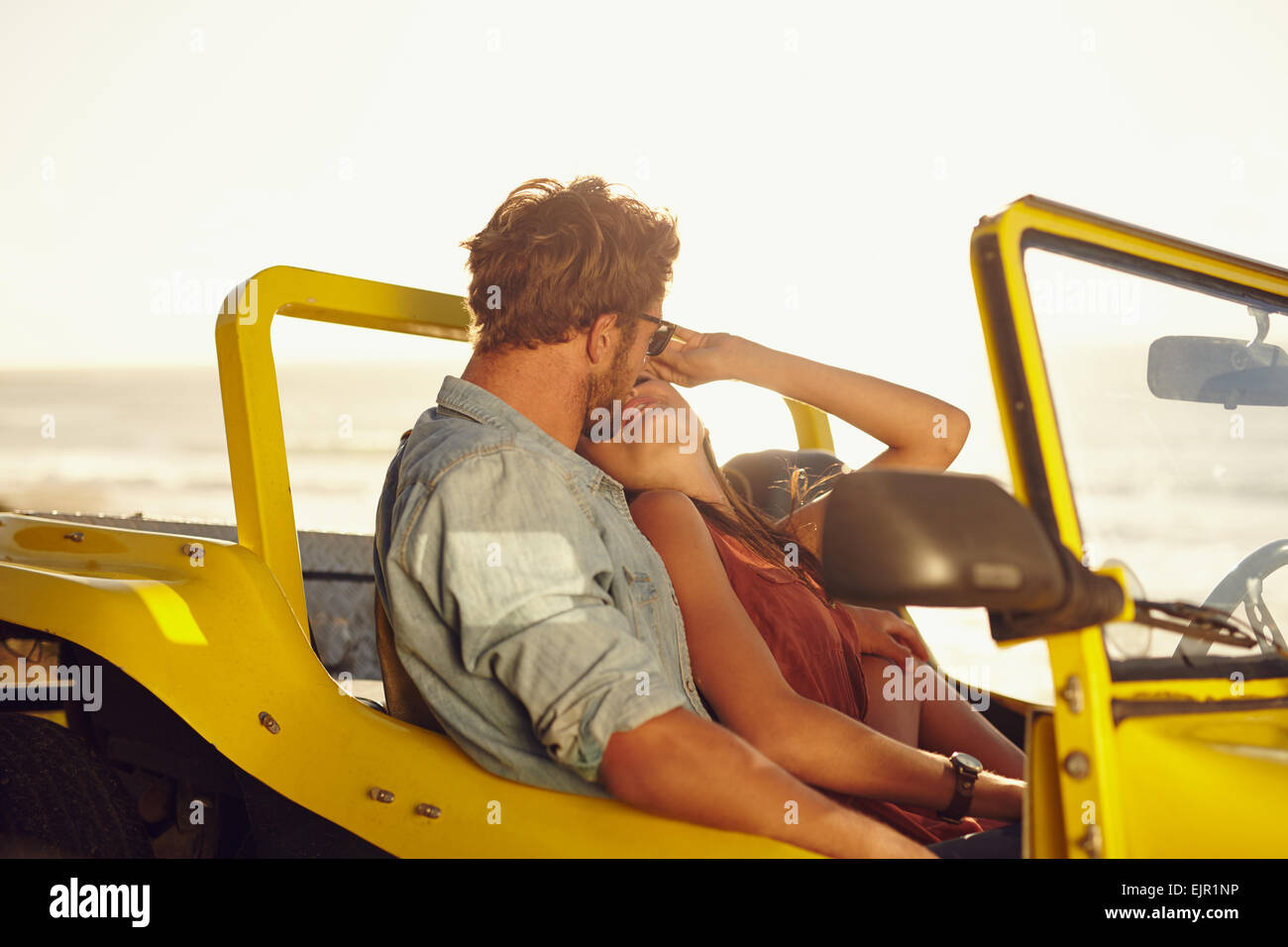 Affettuosa coppia giovane in un'auto. Coppia giovane la condivisione di un momento romantico durante un viaggio. Foto Stock