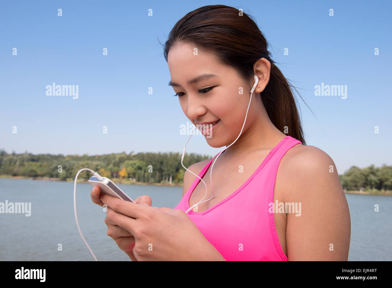 Giovane donna utilizzando smart phone durante l'esercizio Foto Stock