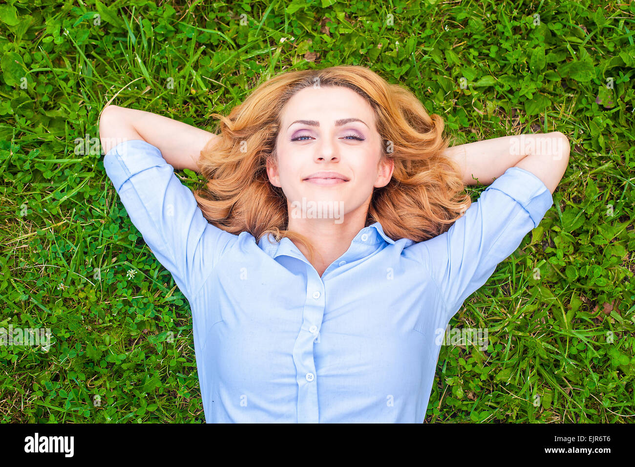 Bella sano giovane donna sdraiata e rilassante sull'erba verde Foto Stock