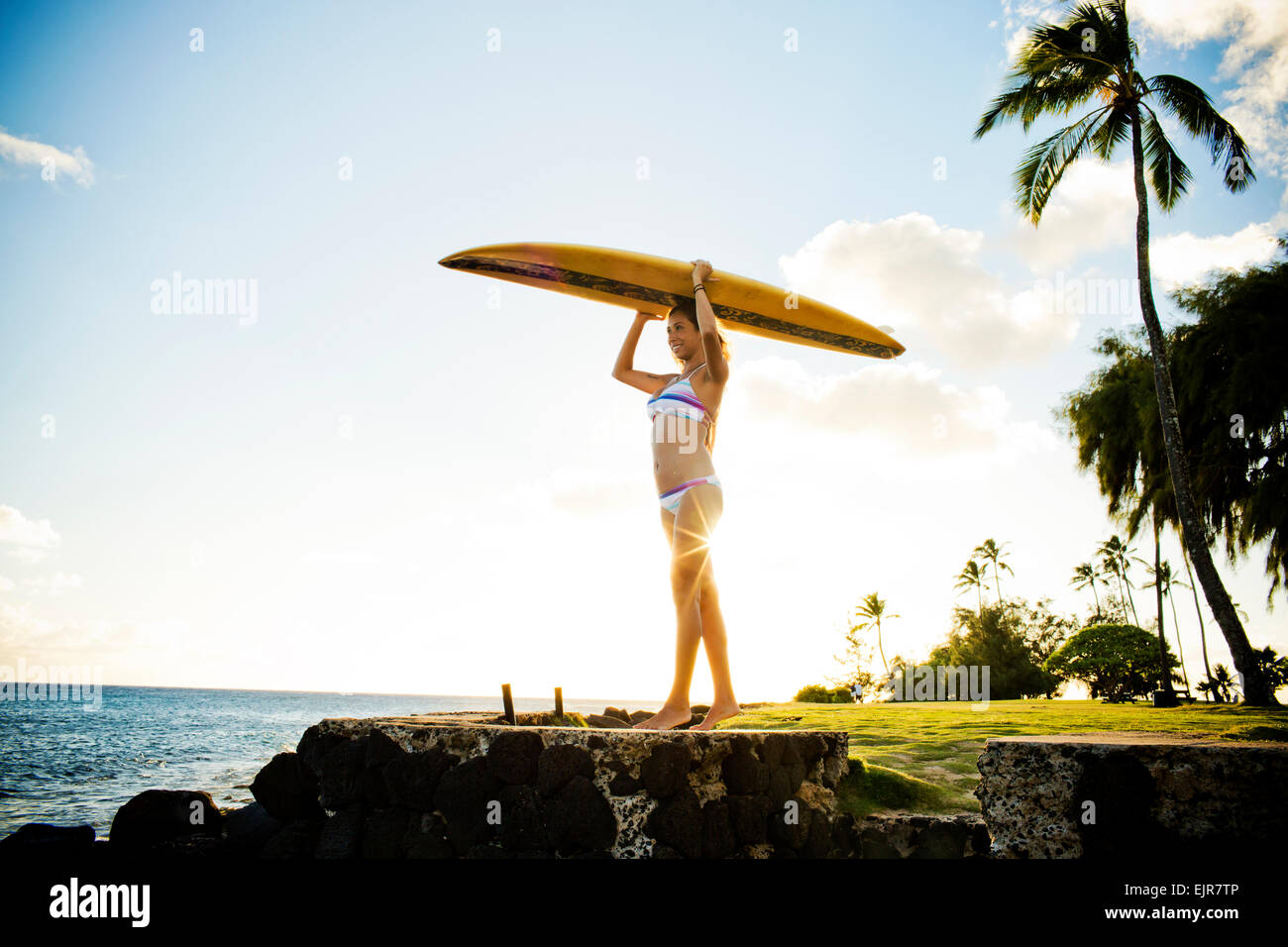 Surfer tenendo le tavole da surf sulla sua testa vicino oceano Foto Stock