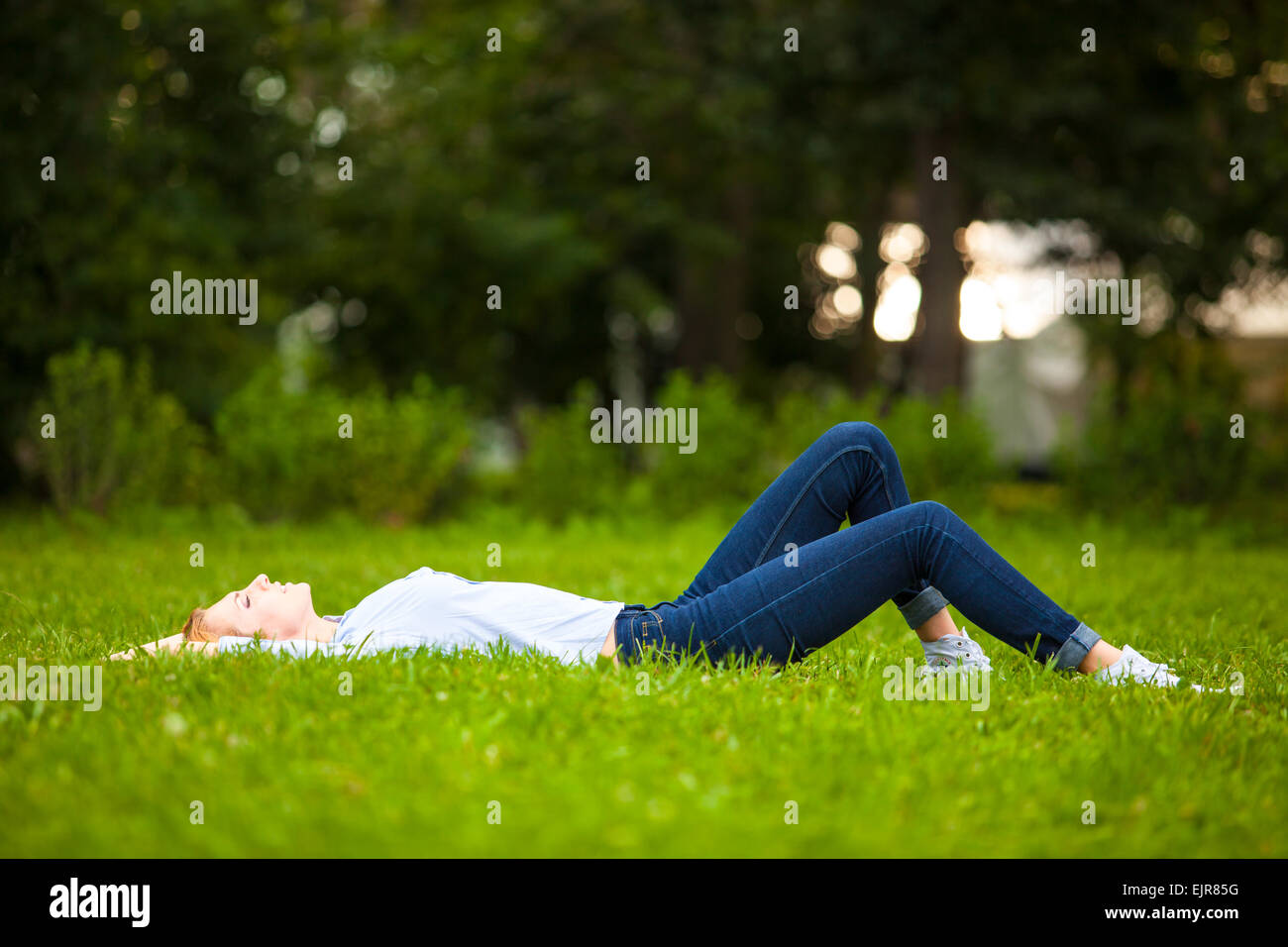 Bella sano giovane donna sdraiata e rilassante sull'erba verde Foto Stock