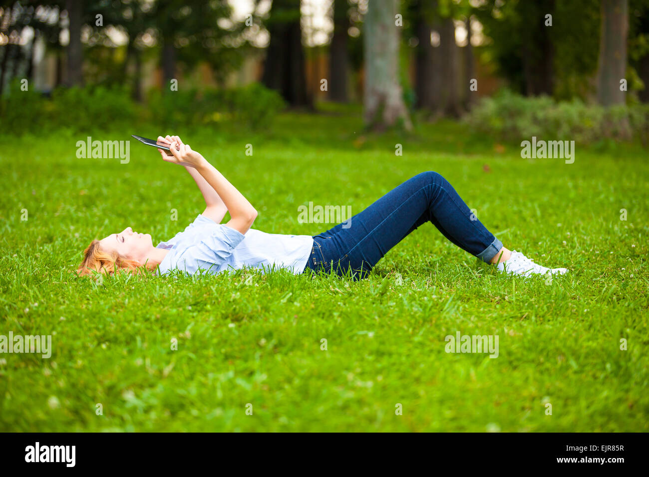 Giovane donna bionda che la lettura di un libro in natura Foto Stock