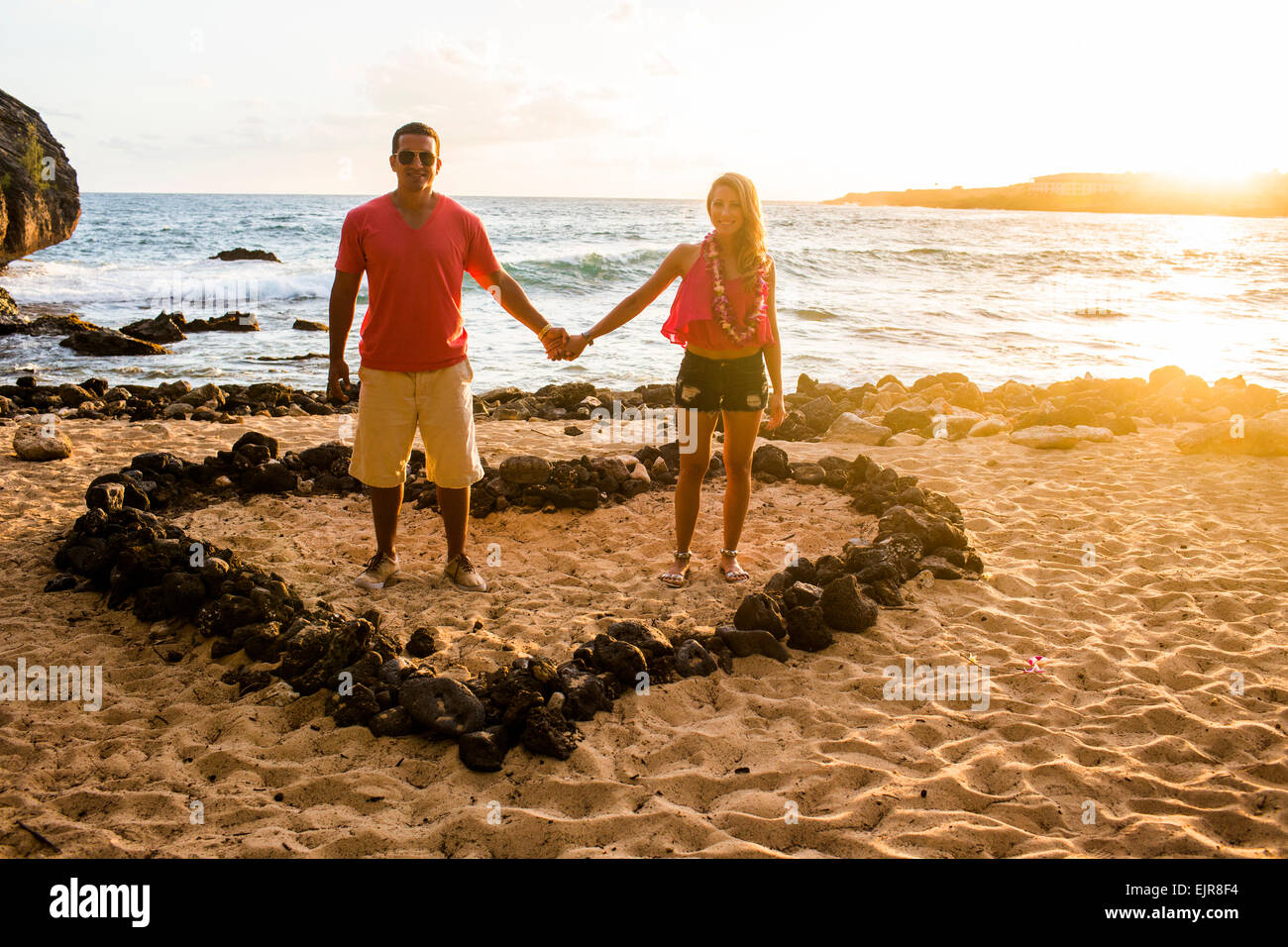 Giovane tenendo le mani a forma di cuore sulla spiaggia Foto Stock