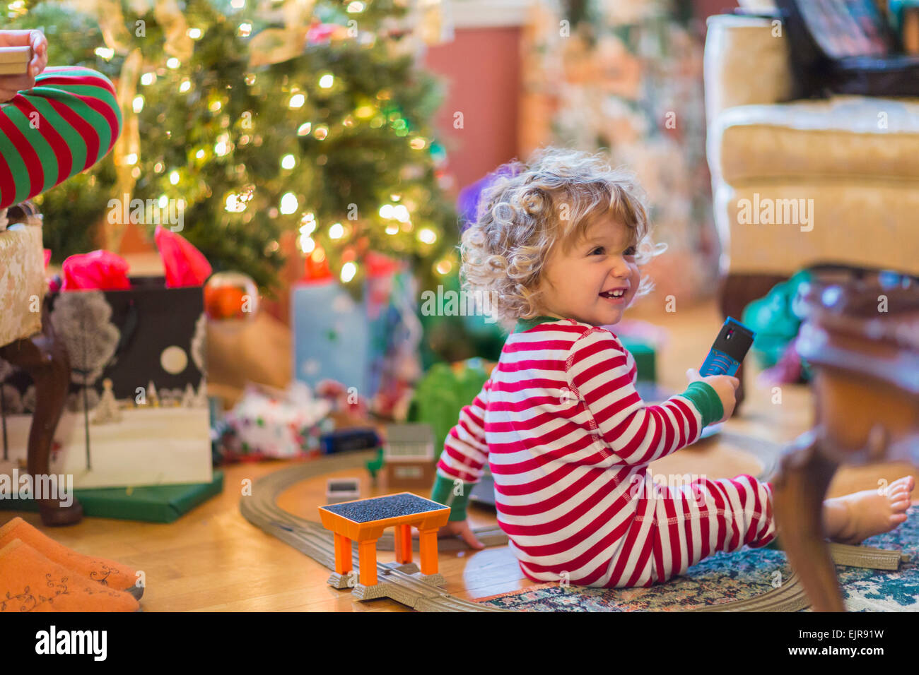 Caucasian baby boy apertura presenta vicino albero di Natale Foto Stock