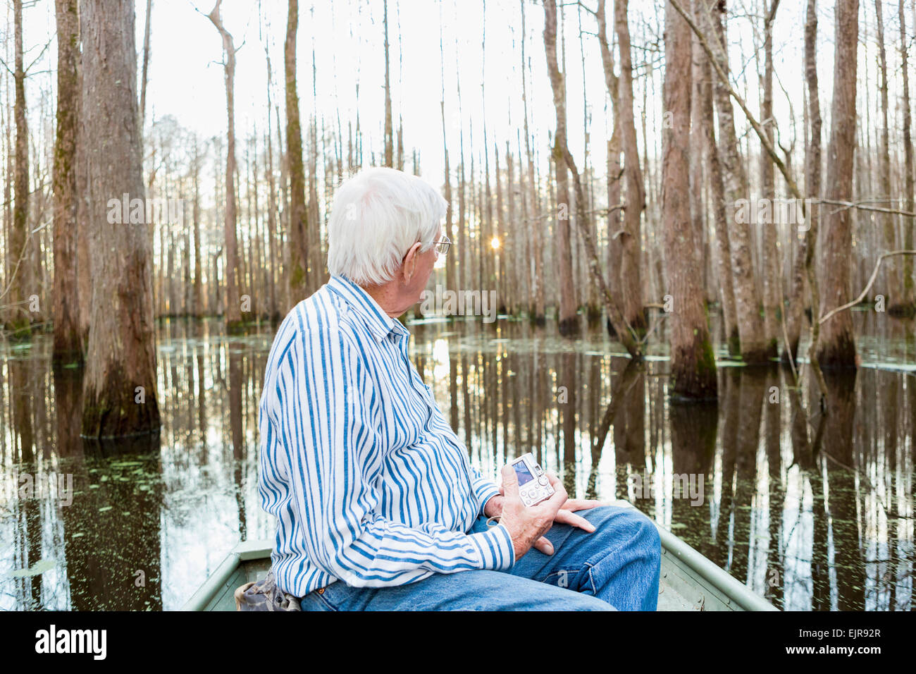 Vecchio uomo caucasico equitazione barca nella palude Foto Stock